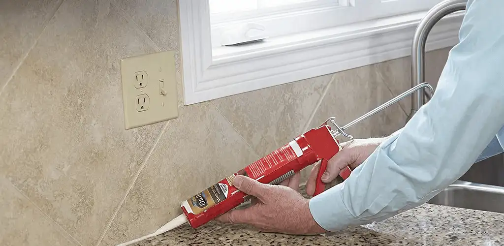 Handyman applying caulk along a kitchen backsplash and countertop seam in Anaheim, CA