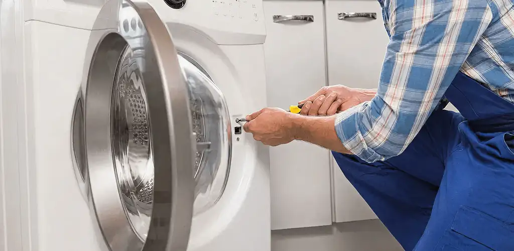 Handyman repairing a clothes dryer and checking electrical connections in Anaheim, CA