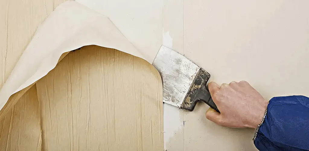 Handyman removing wallpaper with a scraper for wall preparation in Anaheim, CA