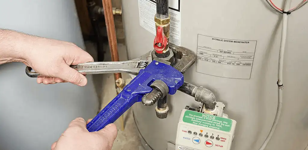 Water heater repair technician tightening the shutoff valve and supply line in Anaheim, CA